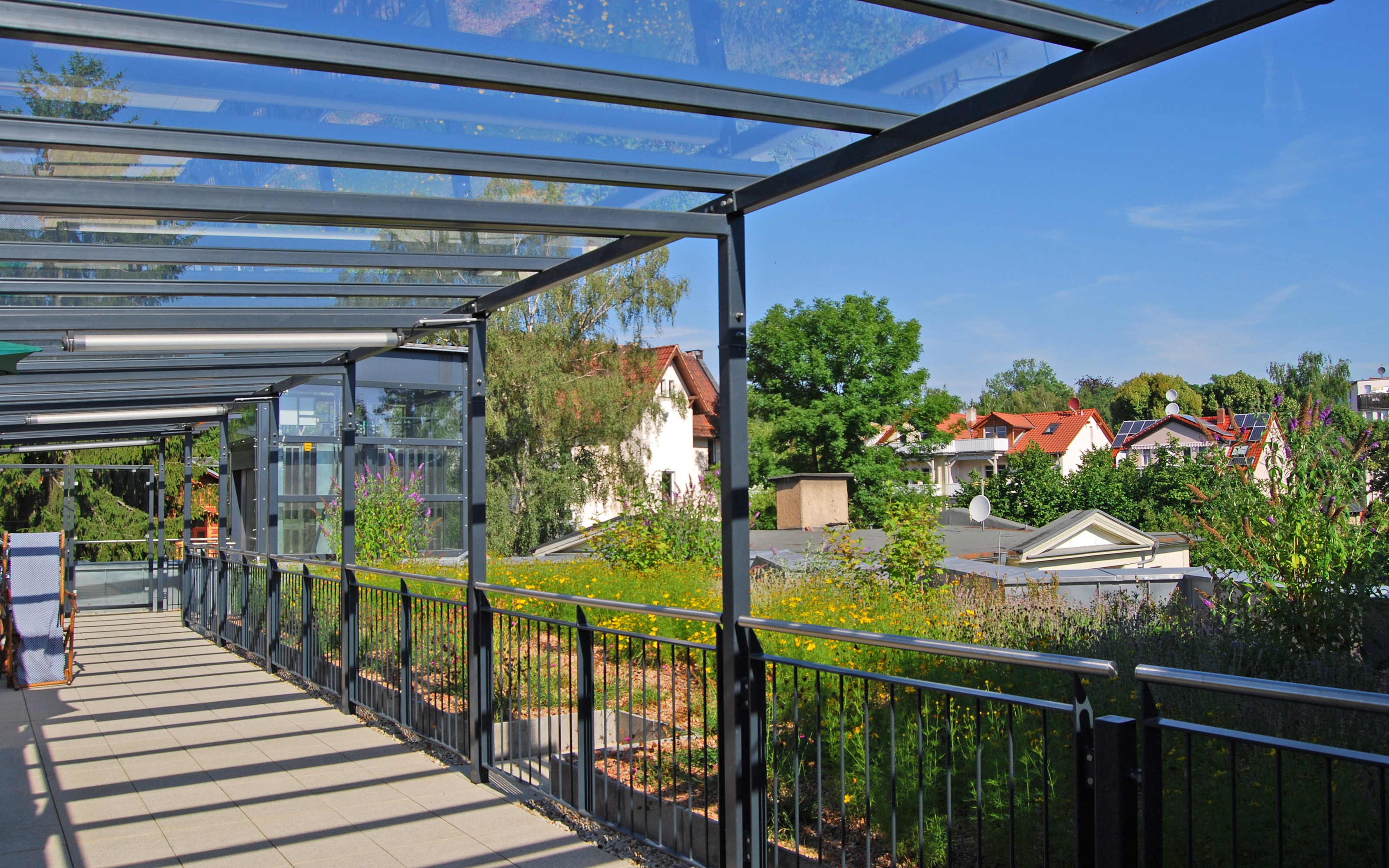 Überdachte Terrasse mit Geländer und Blick auf den begrünten Dachgarten