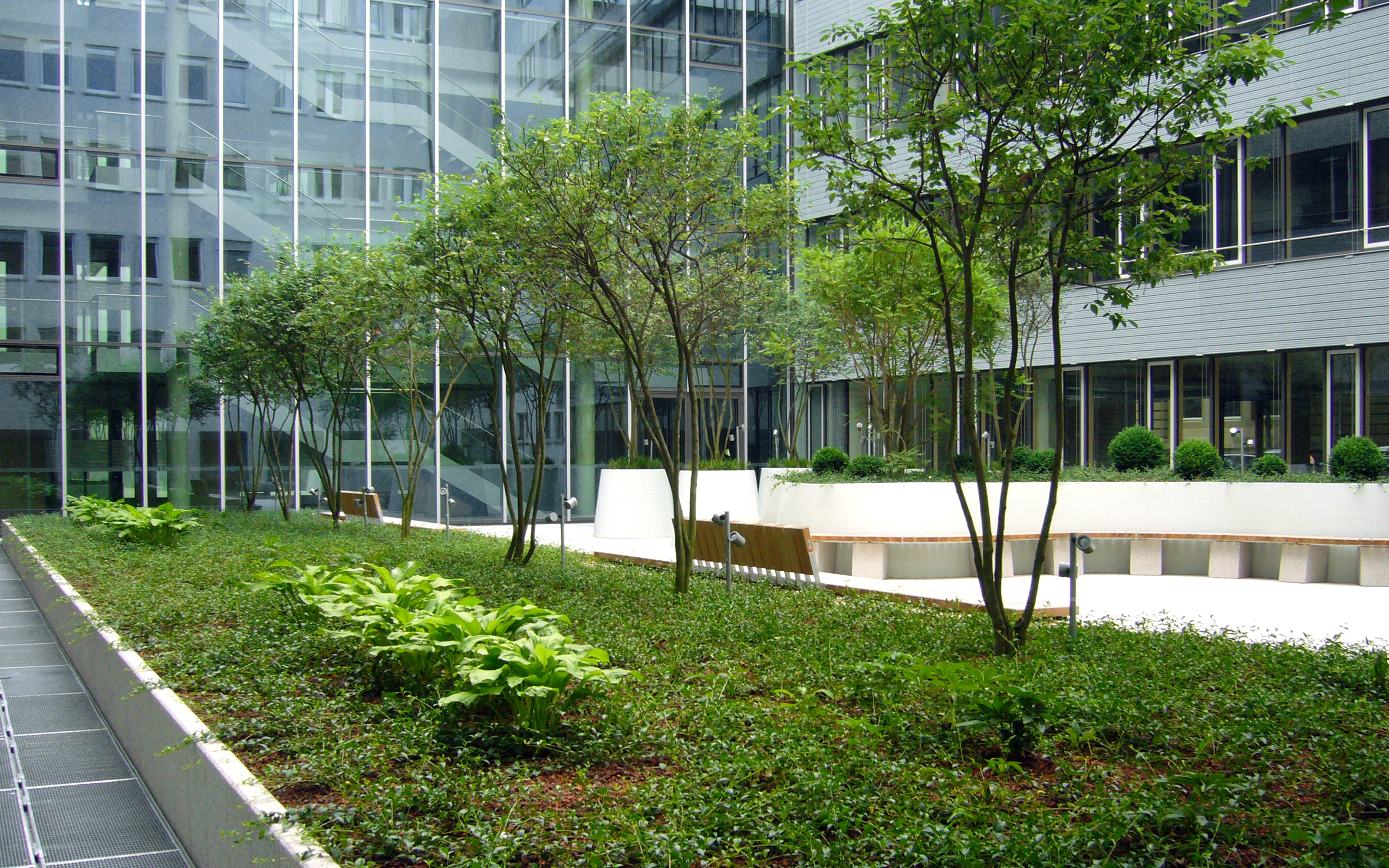 Mit Pflanztrögen und kleinen Bäumen bepflanzter Innenhof eines Bürogebäudes
