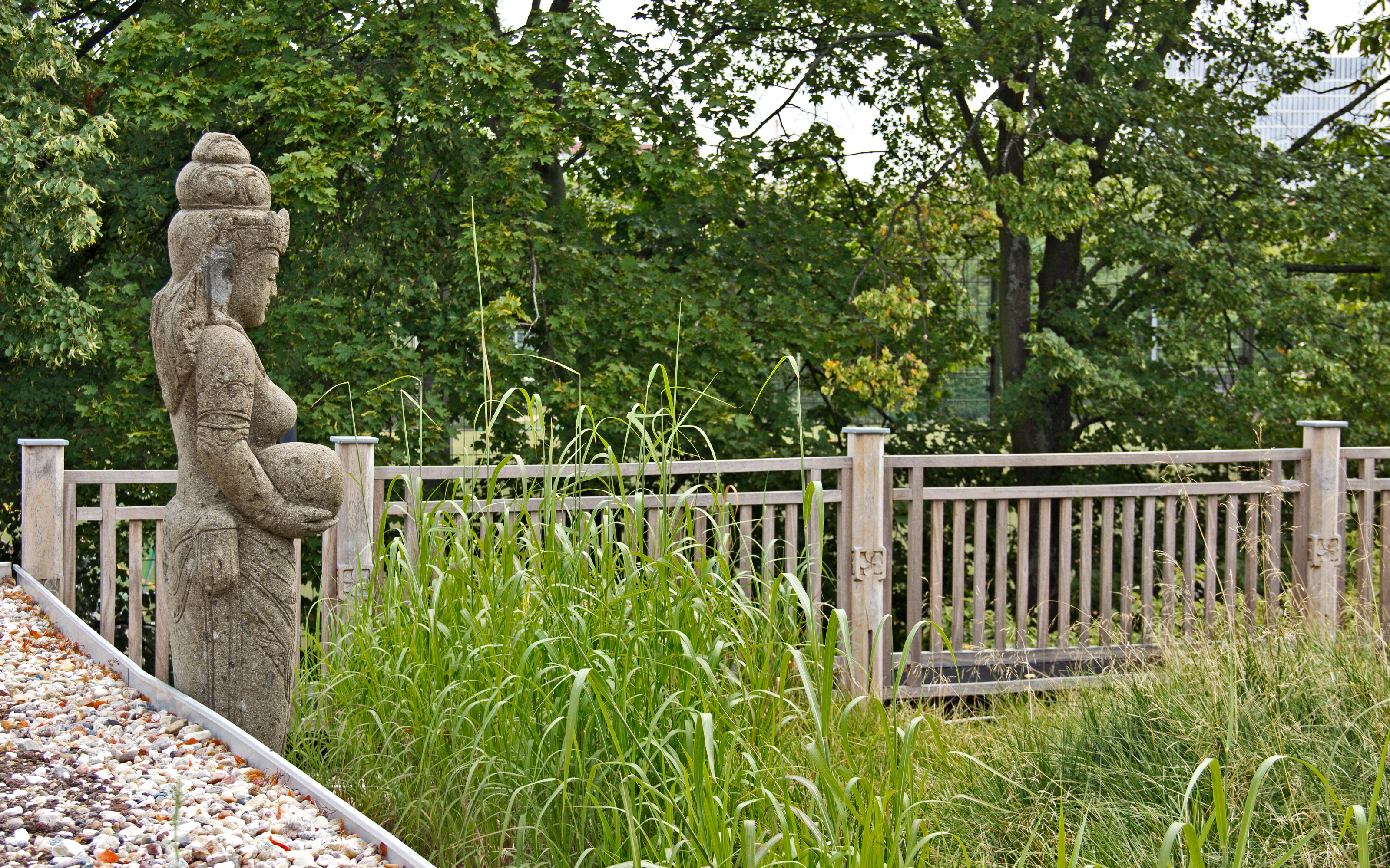 Buddha-Figur vor Gräsern auf einem Dach