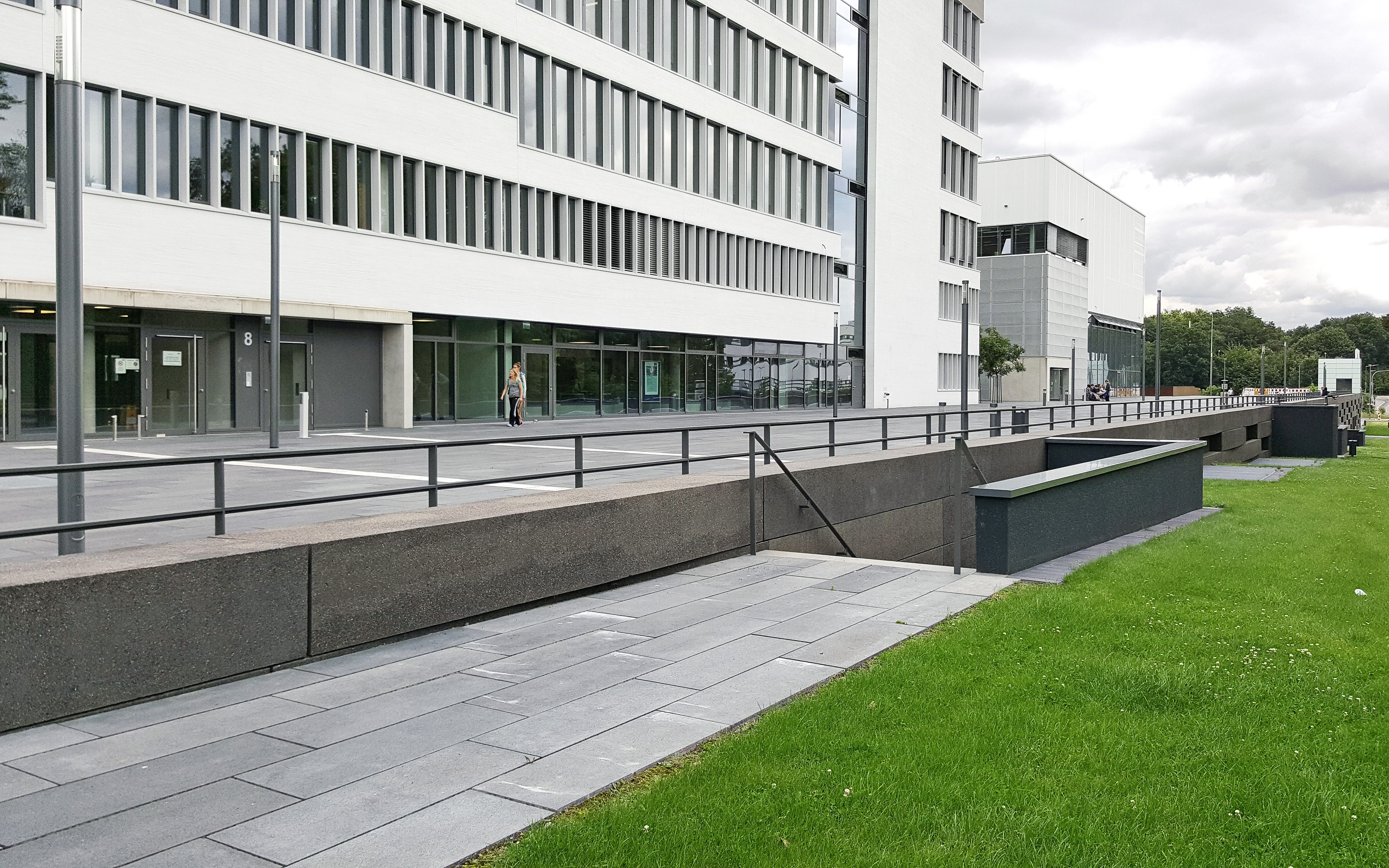 Gehbelagsflächen, Rasen und Tiefgaragenaufgang vor einem Gebäude