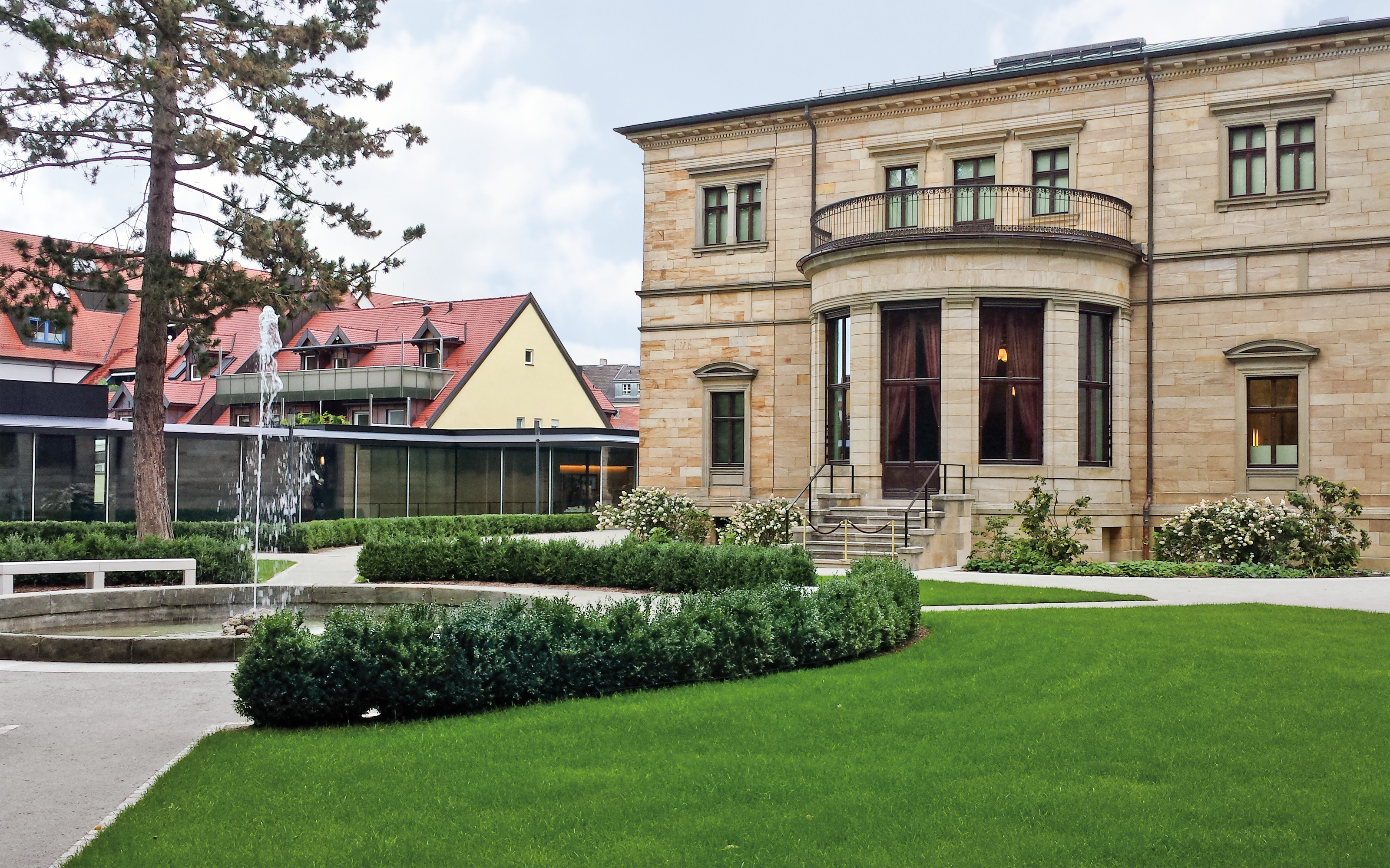 Springbrunnen und Grünflächen vor einem historischen Gebäude