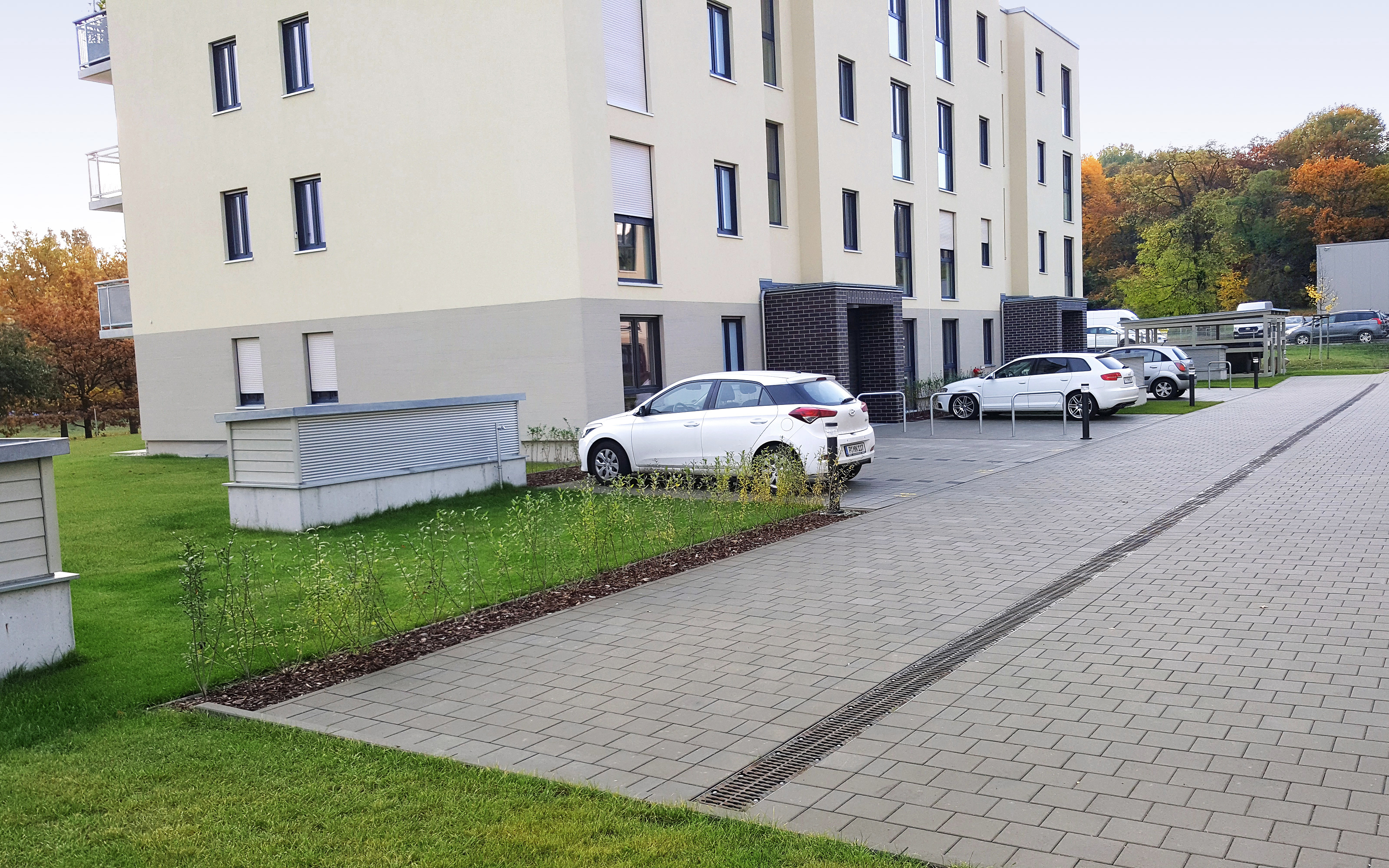 Autostellplätze und Rasen vor einem Mehrfamilienhaus