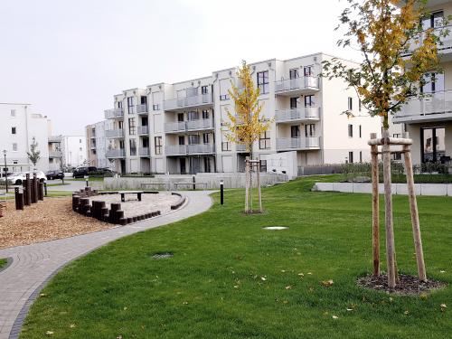 Wohnsiedlung mit Spielplatz, Rasen, kleinen Bäumen und Parkplätzen