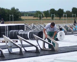 Auf die vollflächig verlegte Dränagebahn Fixodrain® XD 20 (Rollenware) folgen die Solarbasis-Platten SB 200, die jeweils mit einem Solargrundrahmen SGR 35/90 zur Aufständerung der Module bestückt werden. Installation der Solargrundrahmen