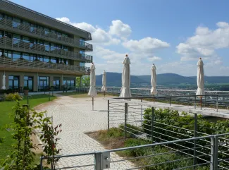 Basis ist hier der ZinCo Systemaufbau „Dachgarten“ mit Floradrain® FD 40. Die Hülsen der Sonnenschirme sind mittels Betonplatten im Begrünungsaufbau fixiert. Dachterrasse mit Gehbelägen, Begrünung und umlaufendes Geländer