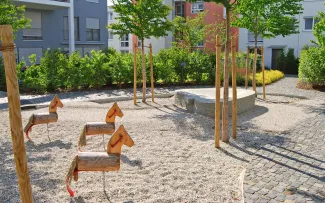 Spielplatz mit Holzpferden, umgeben von Bäumen und Büschen