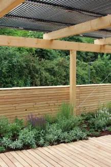 Pergola mit PV-Röhren, Holzterrasse, Intensivbegrünung und Retention – sämtliche Funktionen sind ohne Flächenkonkurrenz verwirklicht. Pergola mit PV-Röhren, Holzterrasse