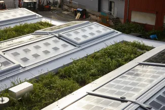 Das Dach besteht aus beweglichen Dachlichtbändern, die sich komplett öffnen lassen und mit Photovoltaikzellen ausgestattet sind – dazwischen ist extensiv begrünt. Quelle: Team MIMO / SDE 21»22 begrüntes Dach