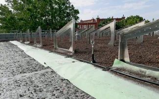 Auf Fixodrain® XD 20 sind die Solarbasisplatten SB 200 mit den Solargrundrahmen platziert. Darüber liegt das Aquafleece® AF 300 (grün) mit seinen Tropfschläuchen. Gründachaufbau mit Fixodrain® XD 20, Aquafleece® AF 300, Solar-Grundrahmen und Substrat